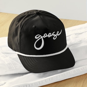 Könnte beinhalten: Schwarze Baseballkappe mit weißem Kordelrand und dem Wort "goose" in weißer Schrift auf der Vorderseite gestickt.
