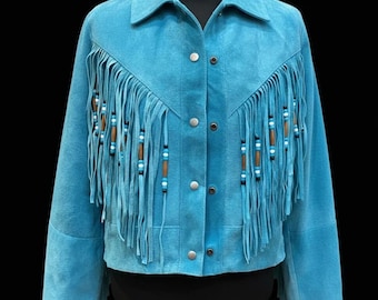 May include: A turquoise suede jacket with fringe detailing and decorative beading. The jacket features a classic collar, button-up front, and long sleeves. The fringe is adorned with brown, white, and blue beads, adding a touch of bohemian flair.