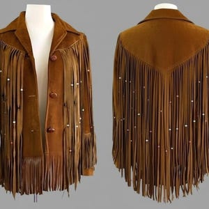 Peut inclure: Veste en daim marron avec longues franges et perles décoratives. La veste a un col, une fermeture à boutons et des franges sur le devant, les manches et le dos. Une pièce d'inspiration vintage.