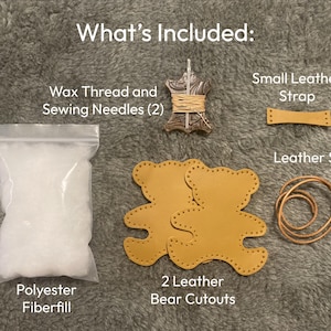 May include: A craft kit labeled What's Included containing a clear bag of white polyester fiberfill, two tan leather bear cutouts with pre-punched holes, a spool of wax thread with two sewing needles, a small tan leather strap, and a tan leather string.
