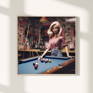 Puede incluir: Una muñeca rubia con una camisa de cuadros rosa y blanca y pantalones vaqueros azules está jugando al billard. La muñeca está de pie detrás de una mesa de billar con una superficie de fieltro azul y un juego de bolas de billar.