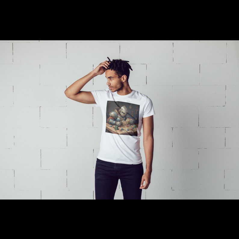 May include: A white t-shirt featuring a graphic print of a knight in armour playing a game of cards. The knight is wearing a helmet and holding a sword. The graphic has a vintage style.