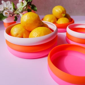 May include: A set of three ceramic nesting bowls in graduating sizes. The bowls are white with a speckled, textured finish and feature a slightly flared rim. The largest bowl measures approximately 8 inches in diameter.