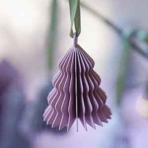 May include: A dusty lavender, accordion-folded paper ornament shaped like a stylised evergreen tree. The ornament features a series of vertical, pleated layers that create a dimensional, fan-like structure, suspended from a light green ribbon loop.