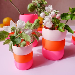 May include: A set of three ceramic mugs with a speckled, matte finish. The mugs are in shades of cream, light gray, and dark gray. Each mug has a simple, minimalist design, perfect for coffee or tea.