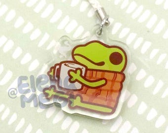 May include: A green frog wearing a red and white plaid shirt is holding a white mug. The frog is a charm on a clear acrylic keychain.