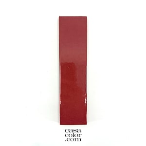 May include: A rectangular, glossy, red tile. The tile is a solid color with a smooth surface. The bottom right corner of the tile has the text "casa color .com".