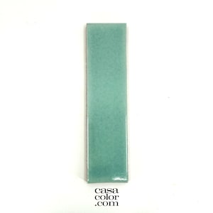 May include: A rectangular, seafoam green tile with a glossy finish. The tile is approximately 6 inches long and 2 inches wide. The bottom right corner of the tile has the text "casa color .com".