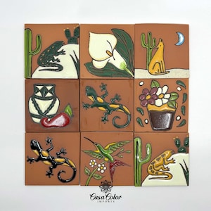 May include: Nine terracotta tiles with colorful hand-painted designs. The tiles feature images of lizards, hummingbirds, cacti, a flower pot, a vase, a pepper, and a coyote.