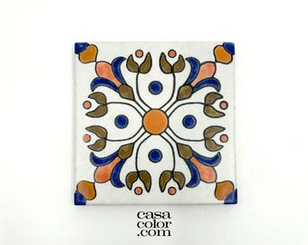 May include: A white ceramic tile with a blue, orange, and brown floral pattern. The tile has a square shape and is decorated with a repeating design of stylized flowers and leaves.