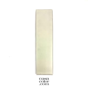 May include: A rectangular, off-white tile with a slightly textured surface. The tile is positioned vertically against a white background. The bottom right corner displays the text "casa color .com".