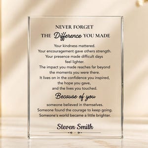 May include: A rectangular clear acrylic plaque featuring black printed text that reads: NEVER FORGET THE DIFFERENCE YOU MADE, followed by a sentimental message about kindness and impact, ending with the name Steven Smith at the bottom.