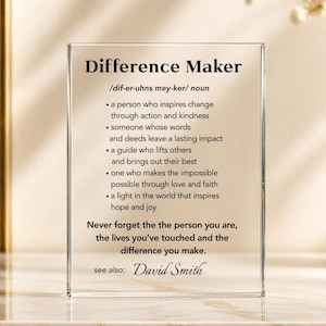 May include: A clear acrylic block with the words "Difference Maker" and a definition. The definition includes phrases like "inspires change" and "lasting impact." The text "Never forget the person you are" is also visible.