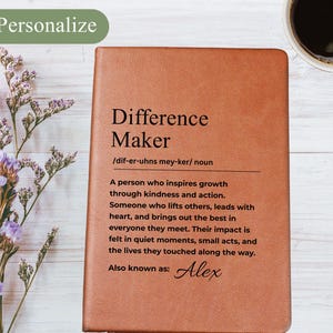 Op de afbeelding: Een bruin leren notitieboek met de woorden "Difference Maker" en een definitie gedrukt op de kaft. Het notitieboek bevat de naam "Alex" en het woord "Personalize" in de linkerbovenhoek.