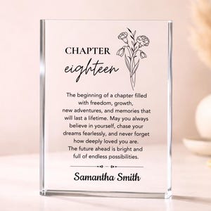May include: A clear acrylic block with the words "CHAPTER eighteen" and a floral illustration. The block contains inspirational text about new beginnings and is personalized with the name "Samantha Smith".