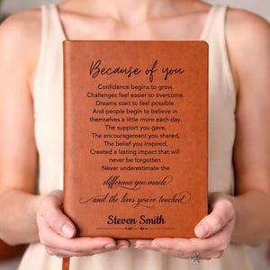Op de afbeelding: Een beige notitieboek in lederlook met de gegraveerde tekst: Because of you, Confidence begins to grow, Challenges feel easier to overcome, Dreams start to feel possible, The difference you made and the lives you've touched, Steven Smith.
