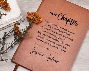 Puede incluir: Un diario de cuero marrón con las palabras "NEW Chapter" y una cita sobre nuevos comienzos. El diario está personalizado con el nombre "Jessica Anderson".