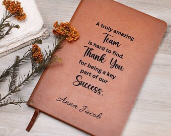 以下が含まれることがあります： 「A truly amazing Team is hard to find. Thank You for being a key part of our Success.」というテキストと「Anna Jacob」という名前が刻まれた、茶色の革製のジャーナルです。