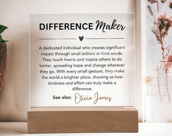 Op de afbeelding: Een heldere acrylplaat met een houten basis, met de tekst "DIFFERENCE Maker" en een citaat over het maken van een verschil door kleine acties. Het citaat wordt toegeschreven aan "Olivia James".