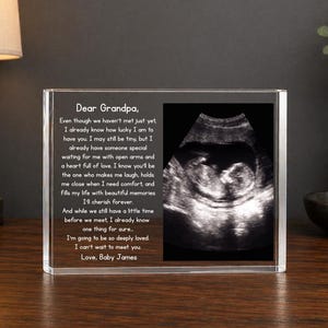 May include: A clear acrylic block with a sonogram image and a heartfelt message to a grandparent. The text reads "Dear Grandpa" followed by a loving message from "Baby James."