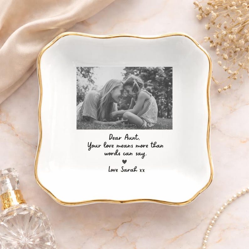 May include: White ceramic trinket dish with a gold rim, featuring a black and white photo of two people. The dish has the text "Dear Aunt, Your love means more than words can say. Love Sarah xx."