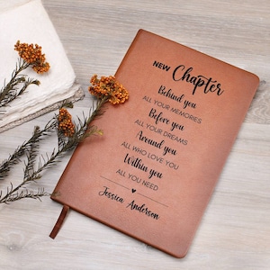 May include: A brown leather journal with the words "NEW Chapter" and a quote about life's journey. The journal is personalized with the name "Jessica Anderson".
