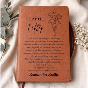 May include: A brown leather journal with the words "CHAPTER Fifty" and a floral illustration. The journal includes an inspirational message and the name "Samantha Smith" at the bottom. A perfect gift for a milestone birthday.