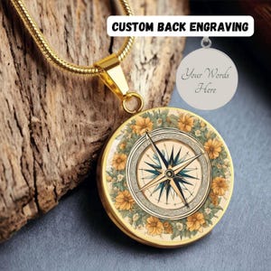 May include: Gold necklace with a compass pendant surrounded by yellow flowers. The back of the pendant can be engraved with a custom message. "Your Words Here" is shown on the back of the pendant.