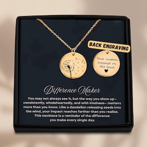 May include: A gold-colored necklace with a round pendant featuring a dandelion design. The necklace is displayed in a black box with the words "Difference Maker" and a message about making a difference.