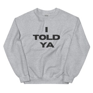 Könnte beinhalten: Ein graues Sweatshirt mit dem Text "I TOLD YA" in Schwarz gedruckt.