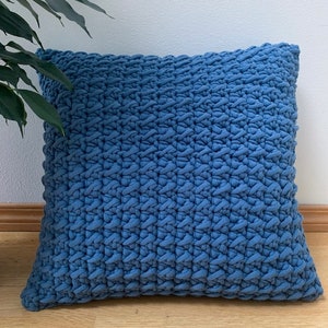 May include: A blue knitted cushion with a textured surface.