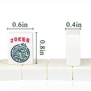 May include: White mahjong tiles, approximately 2 cm tall, 1.5 cm wide, and 1 cm thick. One tile displays the word "JOKER" in red and a green and black design. The tiles are arranged in a row.