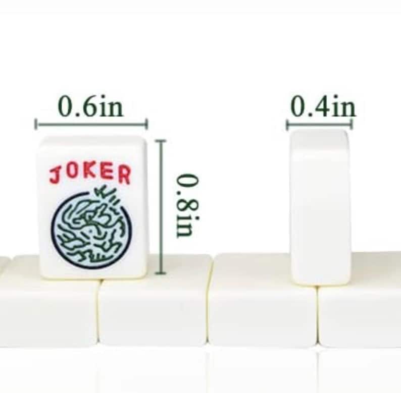 May include: White mahjong tiles, approximately 2 cm tall, 1.5 cm wide, and 1 cm thick. One tile displays the word "JOKER" in red and a green and black design. The tiles are arranged in a row.