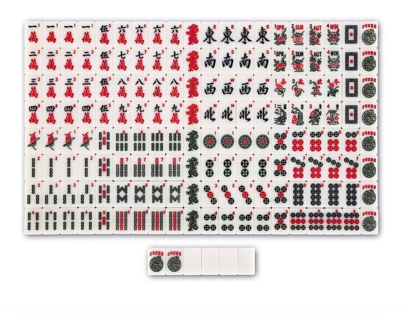 May include: A full set of white Mahjong tiles, marked in red and black with Chinese characters, numbers, and symbols. Several tiles are separate, displaying the word "JOKER". This traditional game set is ready to play.