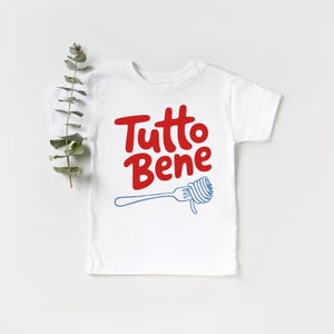 A white t-shirt with the text "Tutto Bene" printed on it, along with a graphic of a fork.