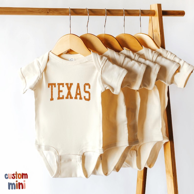three baby onesuits hanging on a clothes rack