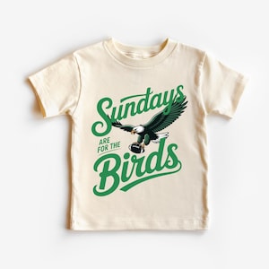 A white t-shirt with a graphic design featuring a green eagle and the text "SUNDAYS ARE FOR THE BIRDS" printed on it.