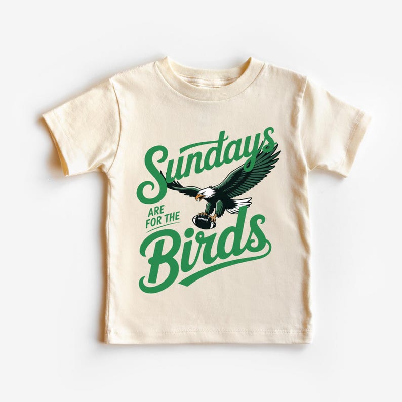 A white t-shirt with a graphic design featuring a green eagle and the text "SUNDAYS ARE FOR THE BIRDS" printed on it.