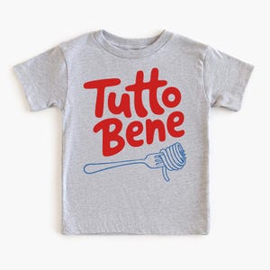 A gray t-shirt with the text "Tutto Bene" printed on it, along with a graphic of a fork with spaghetti.