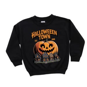 A black sweatshirt with a Halloween-themed graphic design. The design features a large jack-o-lantern and a house, with the text "Halloween Town" and "Est. 1998" printed on the front.