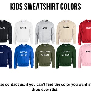 a collection of children's sweatshirt colors, including black, white, ash, sand, red, blue, royal blue, green, forest green, pink, and navy.