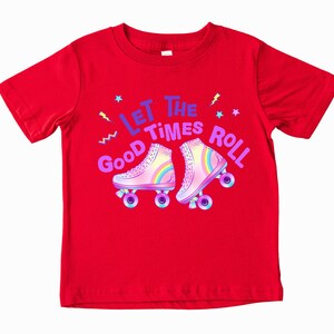 A red t-shirt with a graphic design featuring a pair of rollerblades and the text "Let the good times roll" written above them.