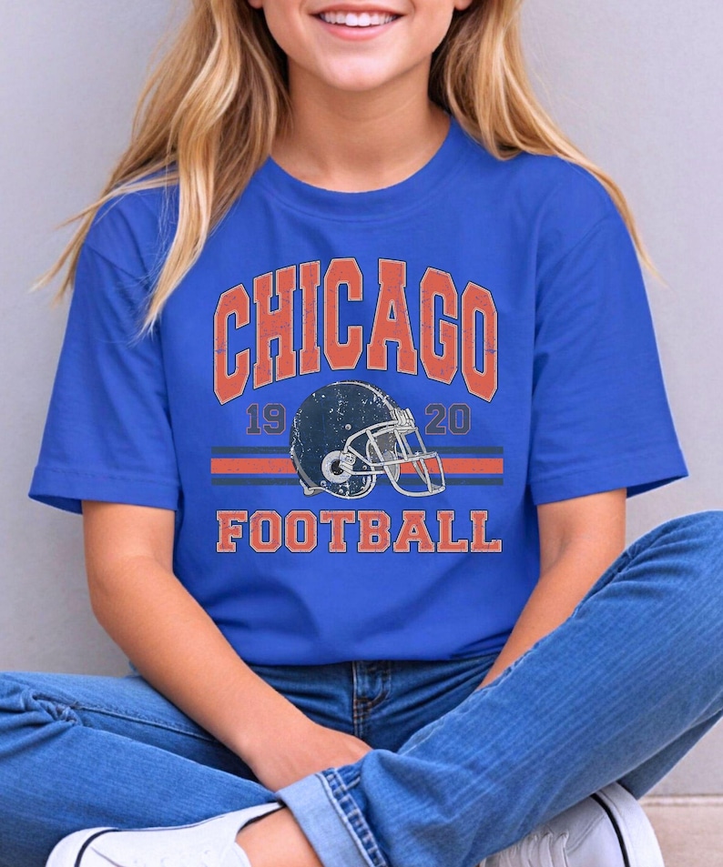 A young woman wearing a blue t-shirt with the text "CHICAGO FOOTBALL" and a graphic of a football helmet.