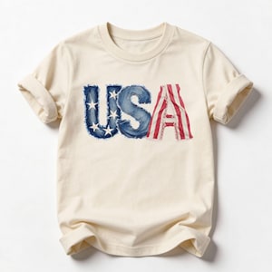 A beige t-shirt with the word "USA" printed on it in stylized lettering.