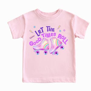 A pink t-shirt with a graphic design featuring two rollerblades and the text "Let the good times roll" in a playful and colorful style.