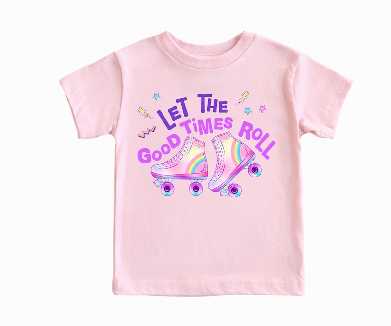 A pink t-shirt with a graphic design featuring two rollerblades and the text "Let the good times roll" in a playful and colorful style.