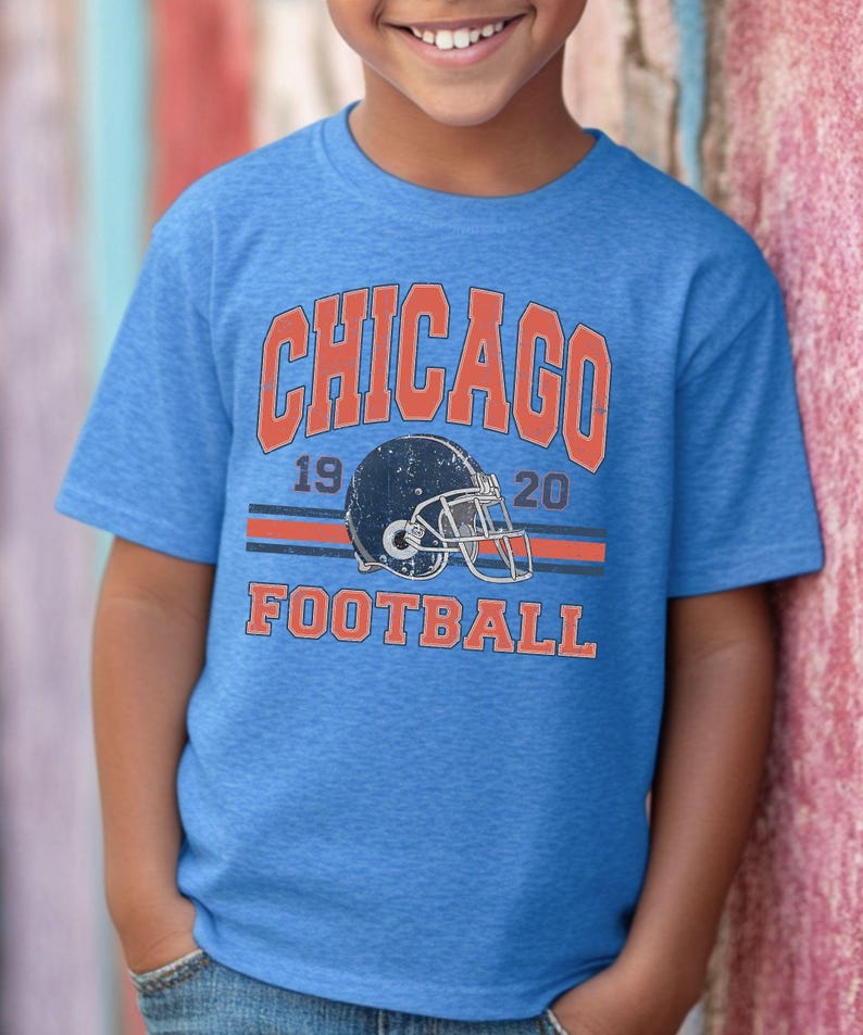 A young boy wearing a blue t-shirt with the text "CHICAGO FOOTBALL" and a graphic of a football helmet.