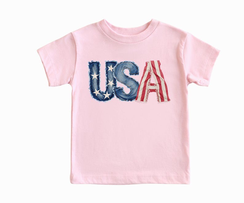 A pink t-shirt with the word "USA" printed on it, featuring the letters in a distressed, distressed-looking style.