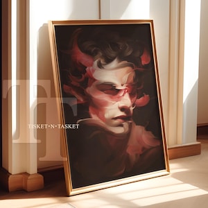 May include: A framed portrait painting featuring a stylized face with red and white hues against a dark background. The artwork is in a gold frame and leans against a white wall. The text "TISKET • N • TASKET" is visible.