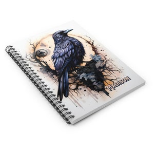 May include: A spiral bound notebook with a watercolor illustration of a raven perched on a branch with a moon in the background. The notebook cover has the name "MADISON" printed on the bottom right corner.